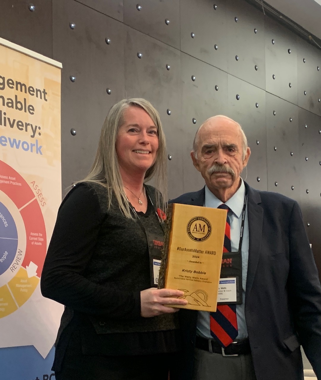 Kristy Bobby from City of Prince George accepting a 2024 #OurAssetsMatter Award from Wally Wells at the 2024 AMBC Conference.